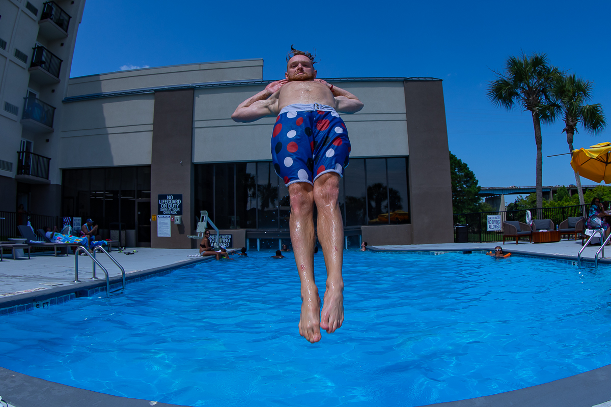 Guy doing incredible floating jump into pool, photo by summer party photographer Beachmonkey