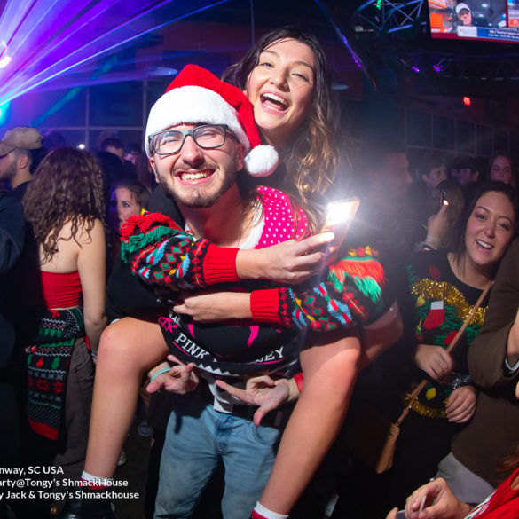 giving a girl a piggy back ride Myrtle Beach Photographer at Tongy's Shmackhouse for the Ugly Christmas Sweater Party Dec 2nd, 2021 in Conway, SC USA by Myrtle Beach photographer Beachmonkey