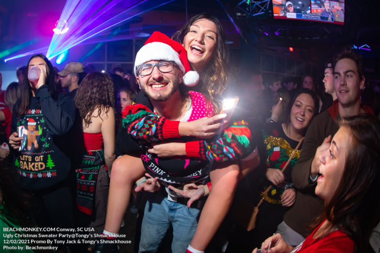 giving a girl a piggy back ride Myrtle Beach Photographer at Tongy's Shmackhouse for the Ugly Christmas Sweater Party Dec 2nd, 2021 in Conway, SC USA by Myrtle Beach photographer Beachmonkey
