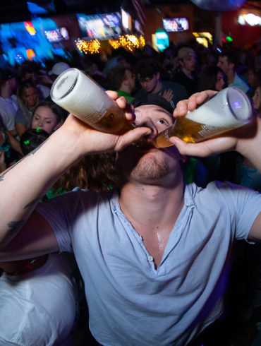 guy chugging two beers at Tongy's Shmackhouse for St Patrick's Day Thurday March 17 2022 in Conway, SC USA photos ﻿Separator ﻿ by Myrtle Beach photographer Beachmonkey