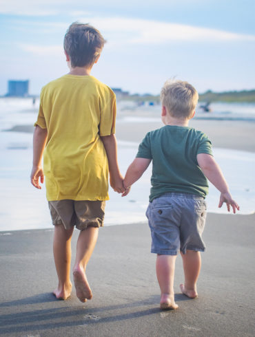 family photo shoot in Myrtle Beach in July 2022 with children holding hands and walking
