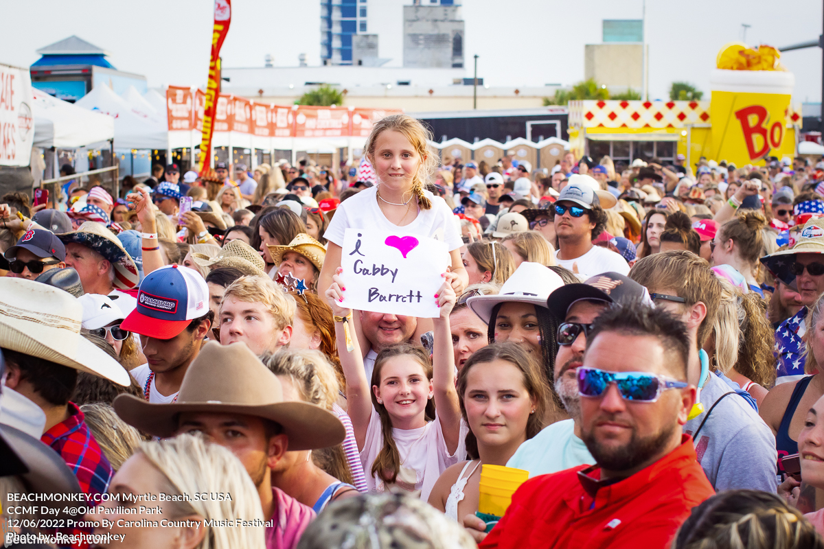girl with sign near girl on shoulders at Carolina Country Music Festival Day Four June 12th, 2022 in Myrtle Beach, SC USA photos by Myrtle Beach photographer Beachmonkey