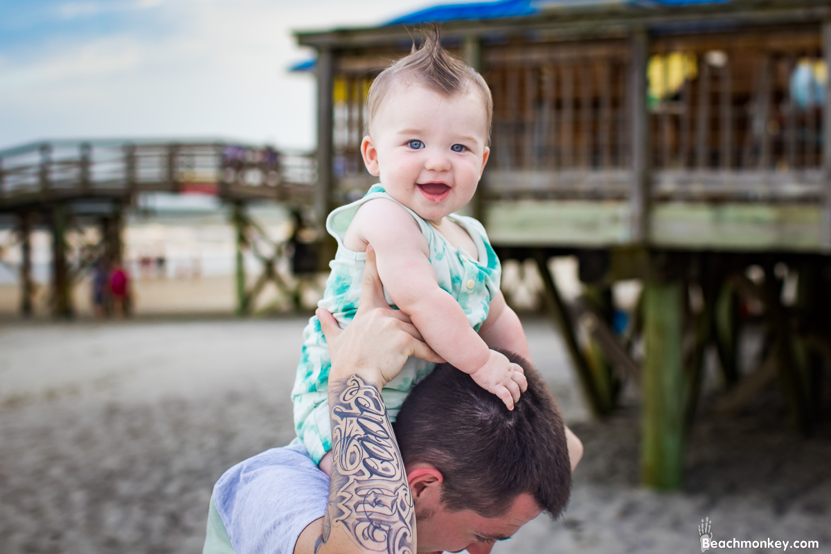 happy baby on father's shoulders A family Beach photo shoot in North Myrtle Beach, SC with Alisha's family by Beachmonkey of beachmonkey photography, a family photographer on July 19th 2022