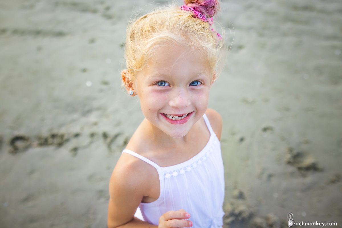 small girl smiling at camera A family Beach photo shoot in North Myrtle Beach, SC with Ashlie's family by Beachmonkey of beachmonkey photography, a family photographer on August 4th 2022