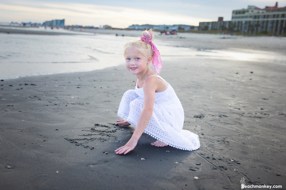 small girl writing name in sand A family Beach photo shoot in North Myrtle Beach, SC with Ashlie's family by Beachmonkey of beachmonkey photography, a family photographer on August 4th 2022