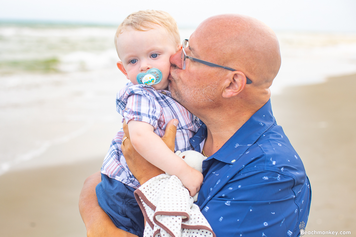 Grandpa kissing baby A family Beach photo shoot in North Myrtle Beach, SC with Bob's family by Beachmonkey of beachmonkey photography, a family photographer August 2022