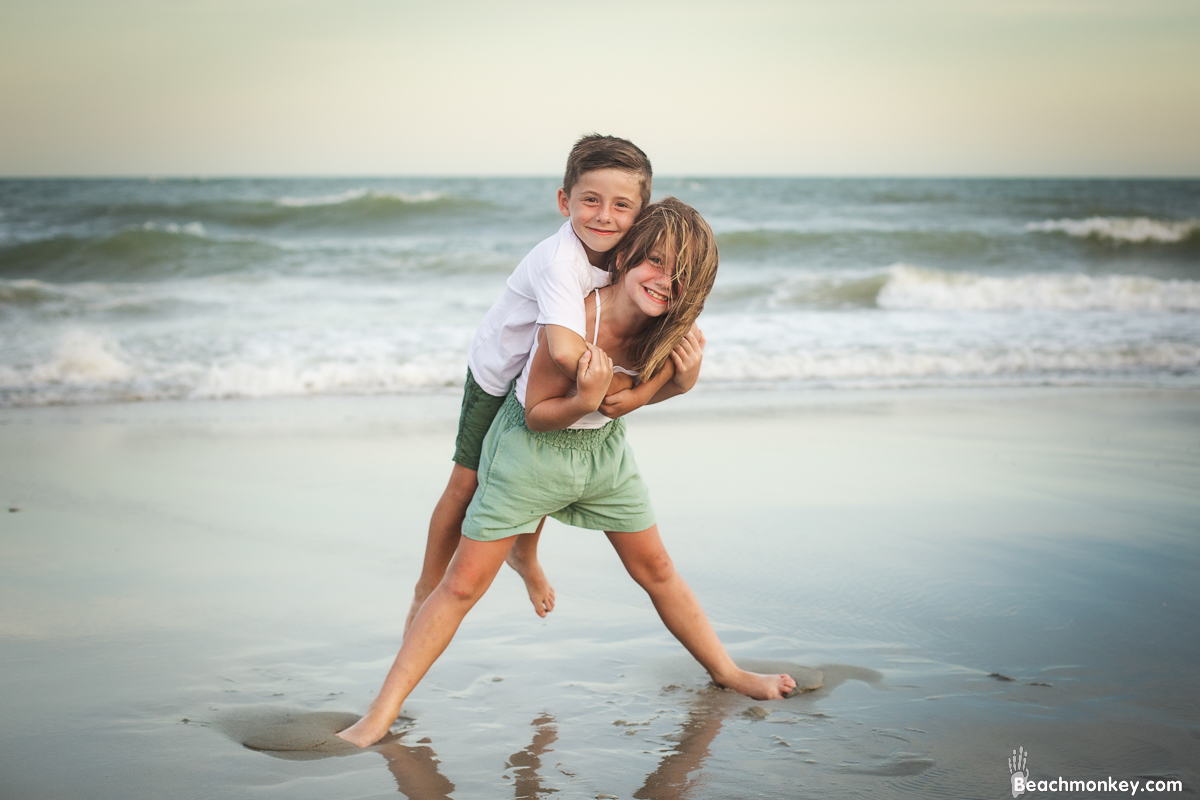 brother and sister piggy back ride at A family photo shoot in Myrtle Beach, SC at Myrtle Beach State Park with Larry's family by Slava of beachmonkey photography, a family photographer July 2022