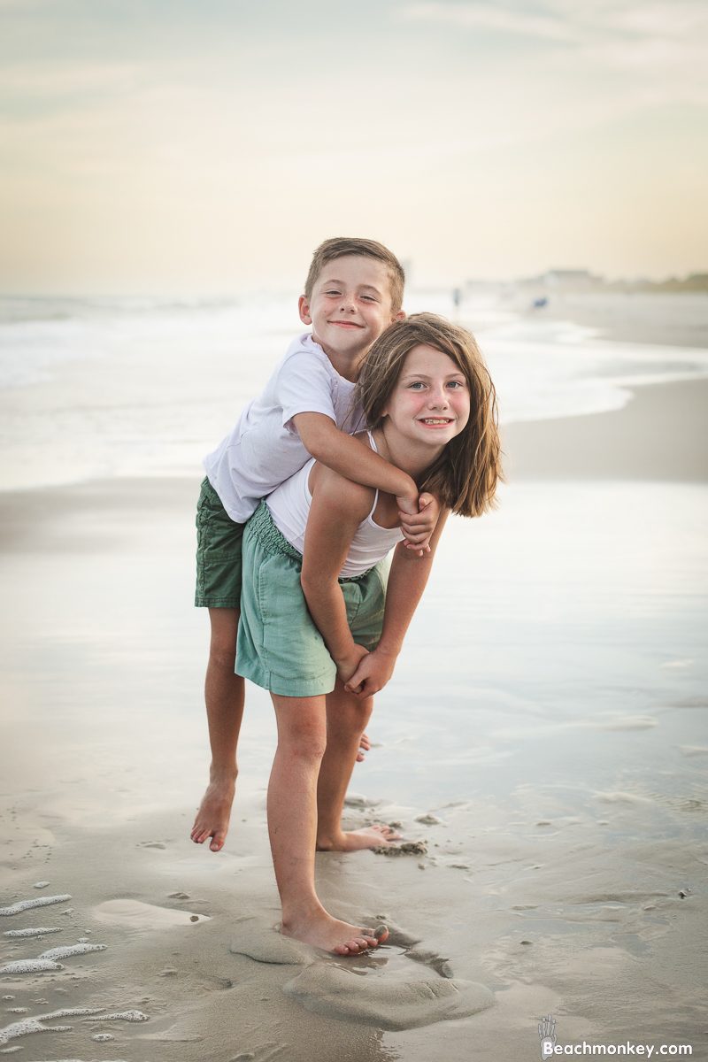 bother and sister piggy back ride at A family photo shoot in Myrtle Beach, SC at Myrtle Beach State Park with Larry's family by Slava of beachmonkey photography, a family photographer July 2022