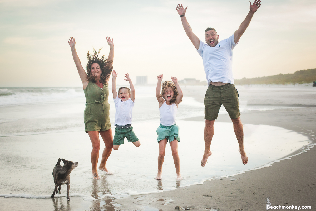 family jumping while dog looks confused at A family photo shoot in Myrtle Beach, SC at Myrtle Beach State Park with Larry's family by Slava of beachmonkey photography, a family photographer July 2022