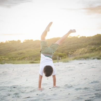 child doing hand stand on the beach at A family photo shoot in Myrtle Beach, SC at Myrtle Beach State Park with Larry's family by Slava of beachmonkey photography, a family photographer July 2022