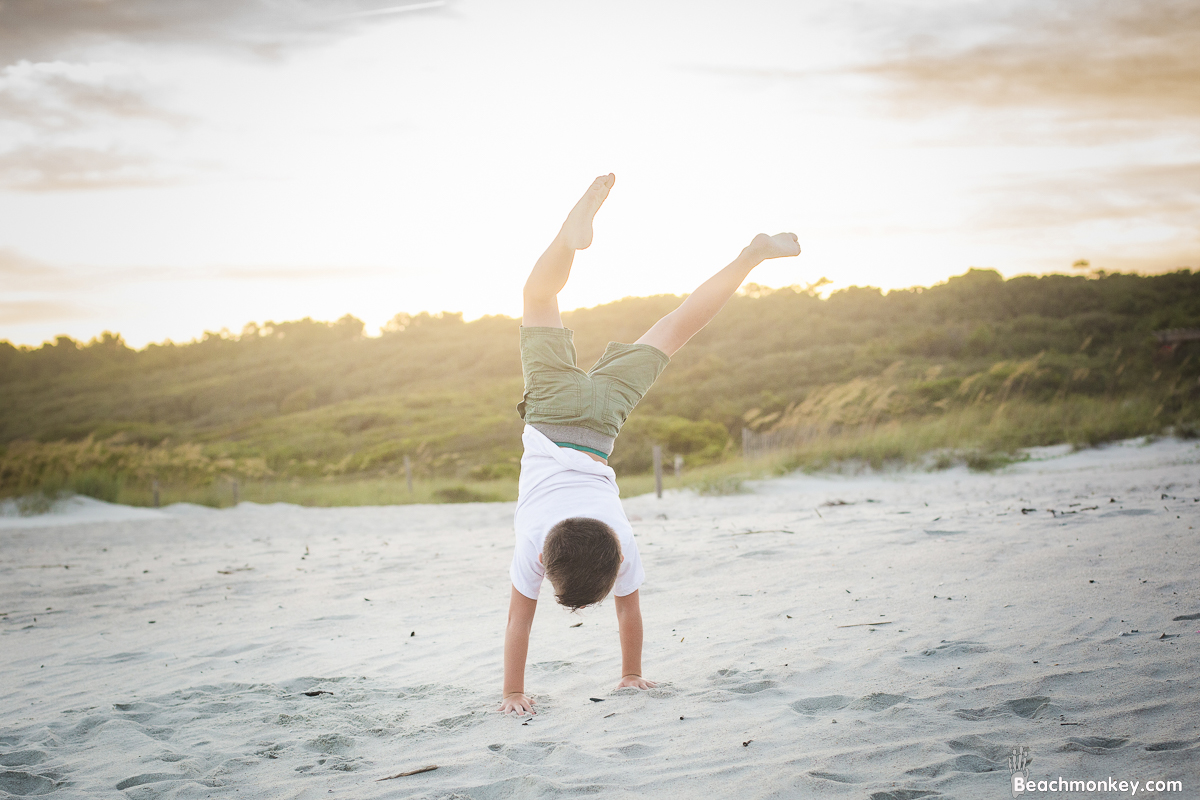 child doing hand stand on the beach at A family photo shoot in Myrtle Beach, SC at Myrtle Beach State Park with Larry's family by Slava of beachmonkey photography, a family photographer July 2022