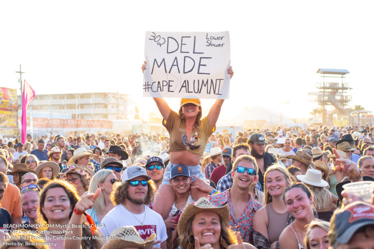 girl holding sign on shoulders in crowd at Carolina Country Music Festival Day three June 11th, 2022 in Myrtle Beach, SC USA photos by Myrtle Beach photographer Beachmonkey