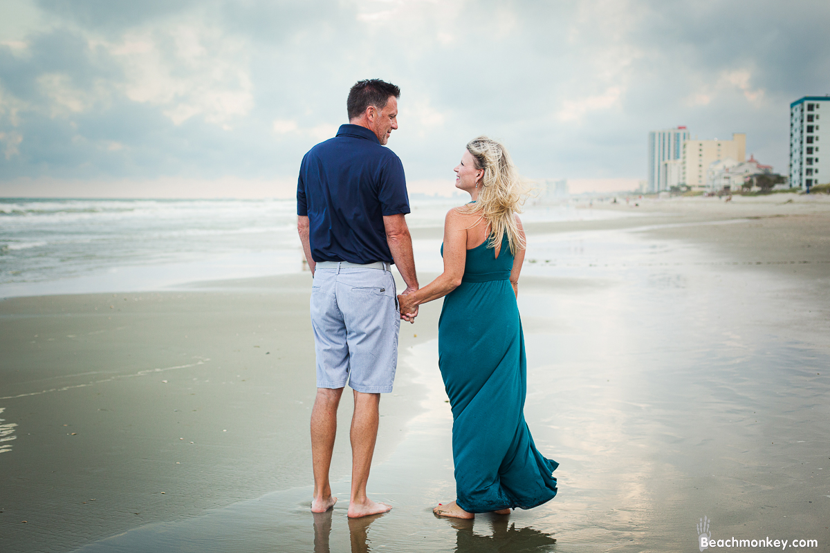 mother and father walking A family Beach photo shoot in North Myrtle Beach, SC with Dana's family by Slava of beachmonkey photography, a family photographer on July 7th 2022