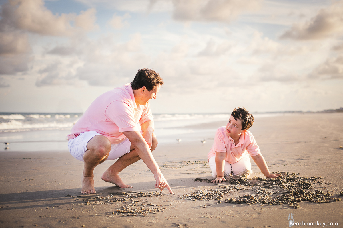 father and son writing in sand A maternity Beach photo shoot in Myrtle Beach, SC USA with Zlata's family by Slava of beachmonkey photography, a maternity photographer on September 4th 2022