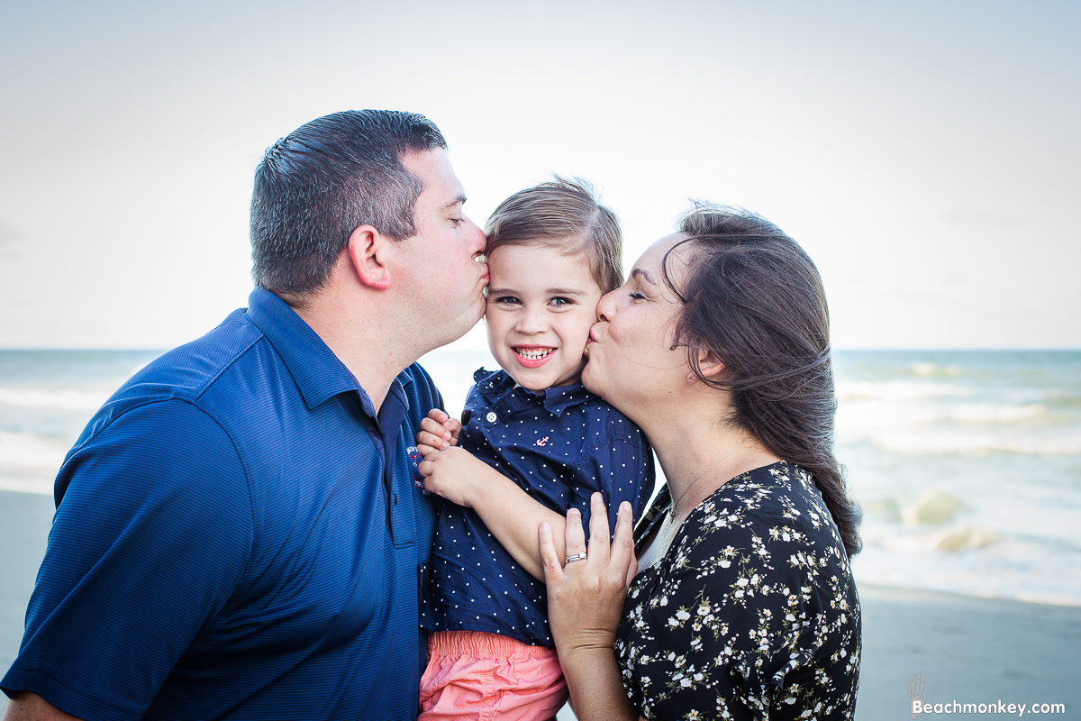 Parents kissing baby A family Beach photo shoot in North Myrtle Beach, SC with Erin's family by Slava of beachmonkey photography, a family photographer on August 8th 2022