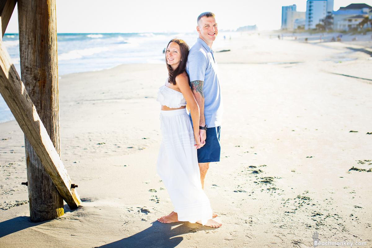 couple standing back to back couple kissing A family Beach photo shoot in North Myrtle Beach, SC with Amanda's family by Beachmonkey of beachmonkey photography, a family photographer on August 8th 2022