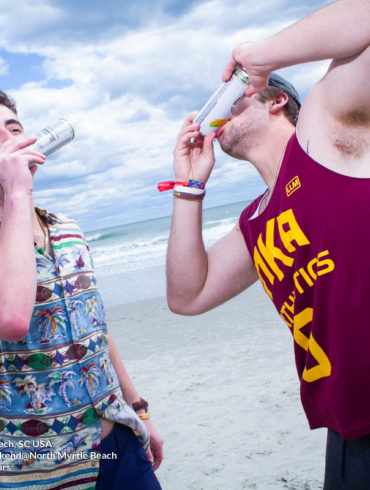 two guys shot gunning beverage Pi Kappa Alpha Virginia Tech Fraternity Beach Weekend in North Myrtle Beach, SC USA sponsored by Myrtlebeachtours.com April 9th 2022 Photos by Napoleon