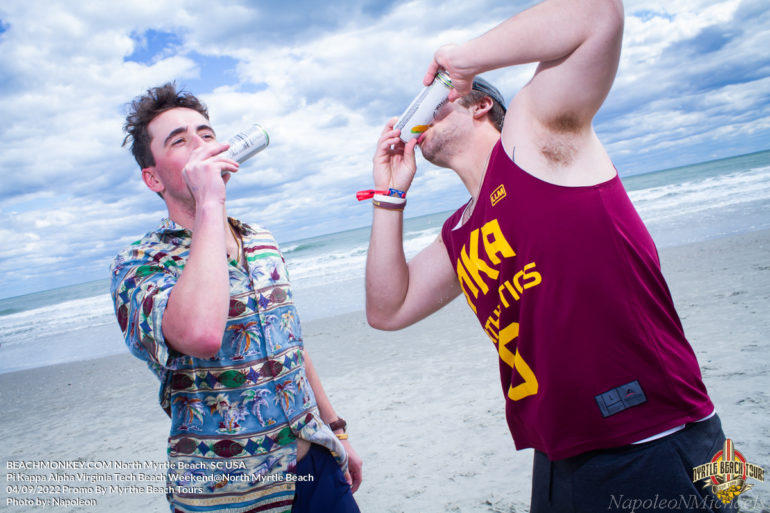 two guys shot gunning beverage Pi Kappa Alpha Virginia Tech Fraternity Beach Weekend in North Myrtle Beach, SC USA sponsored by Myrtlebeachtours.com April 9th 2022 Photos by Napoleon